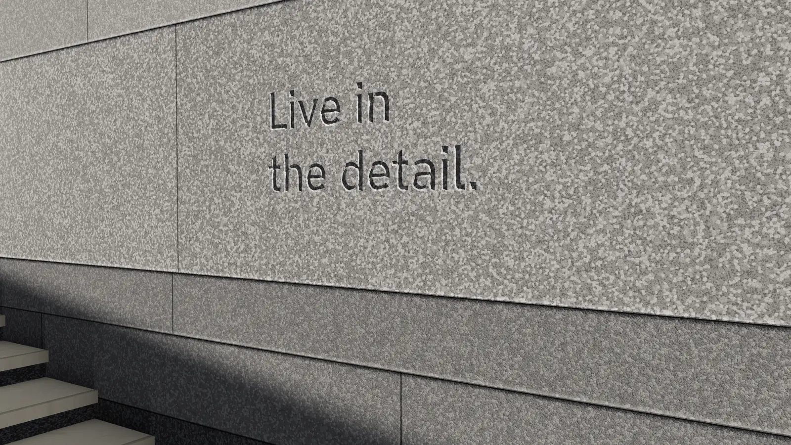 ‘Live in the detail.’ cut into honed granite in raking sun.